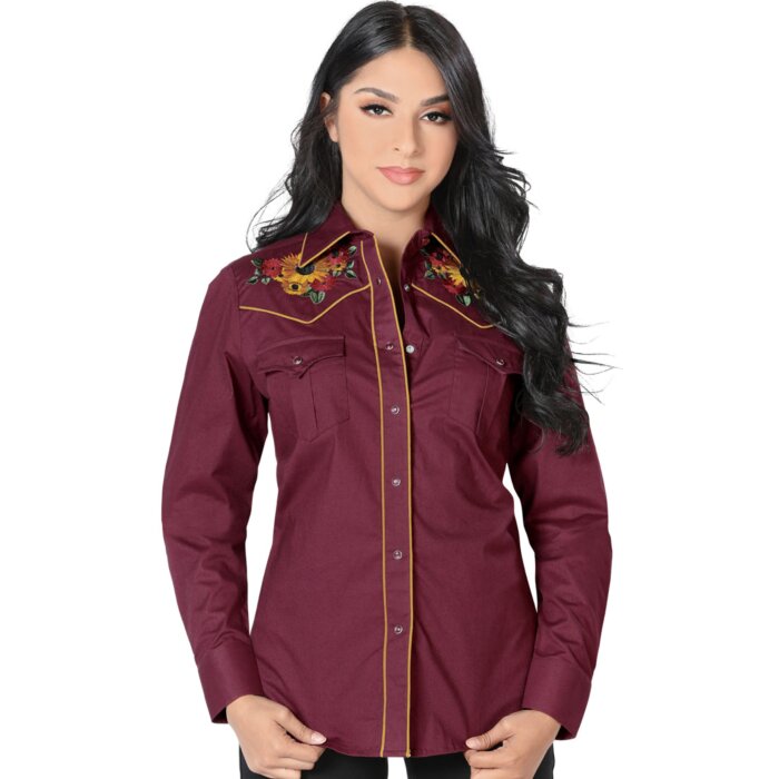 Mujer de pelo negro luciendo blusa vaquera color vino con bordado de girasoles y vivos rojos, botonadura de broche.