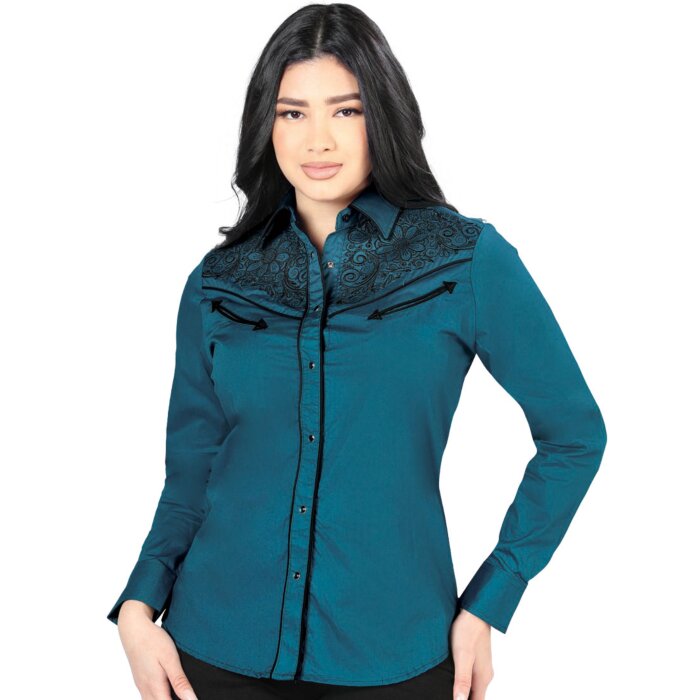 Mujer de pelo negro luciendo blusa vaquera color teal con bordado negro en el frente, botonadura de broche.