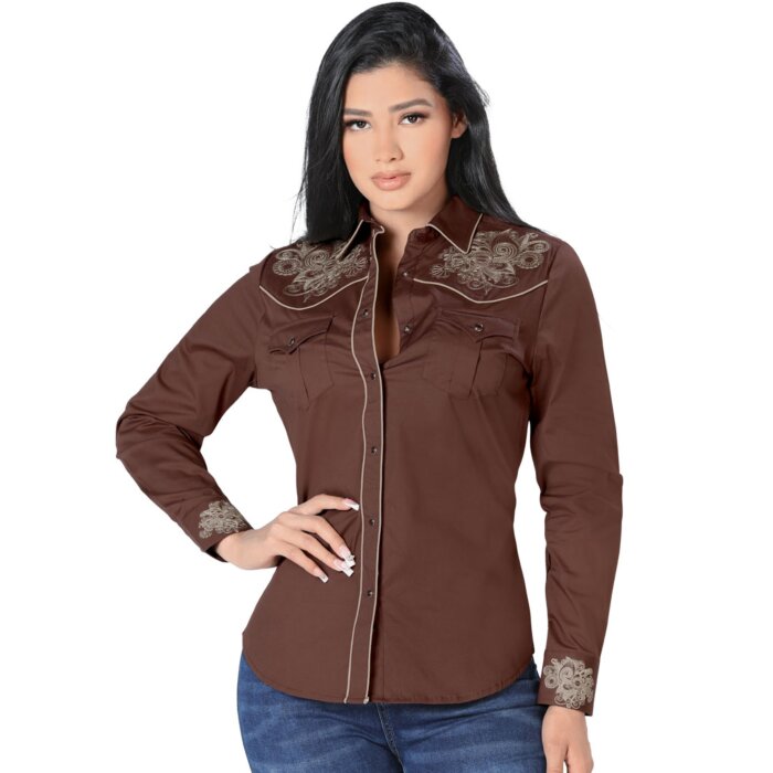 Mujer de pelo negro luciendo blusa vaquera color Café con bordado y vivos beige, botonadura de broche.