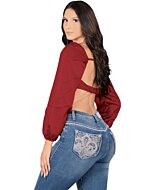 A woman wearing light blue boot cut jeans with intricate embroidered back pockets, paired with a red long-sleeve crop top.