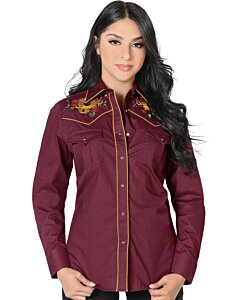 Mujer de pelo negro luciendo blusa vaquera color vino con bordado de girasoles y vivos rojos, botonadura de broche.