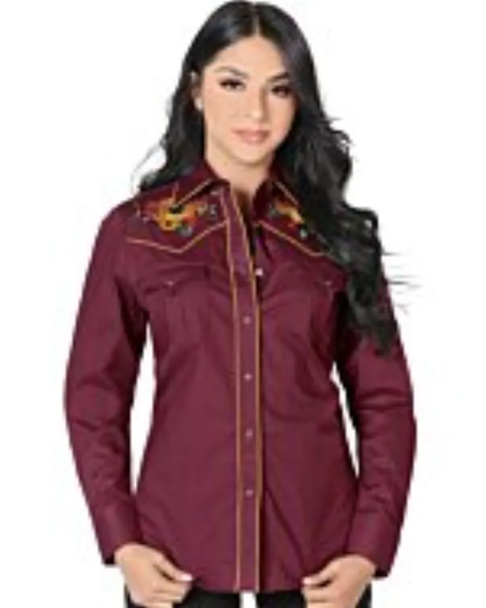 Mujer de pelo negro luciendo blusa vaquera color vino con bordado de girasoles y vivos rojos, botonadura de broche.